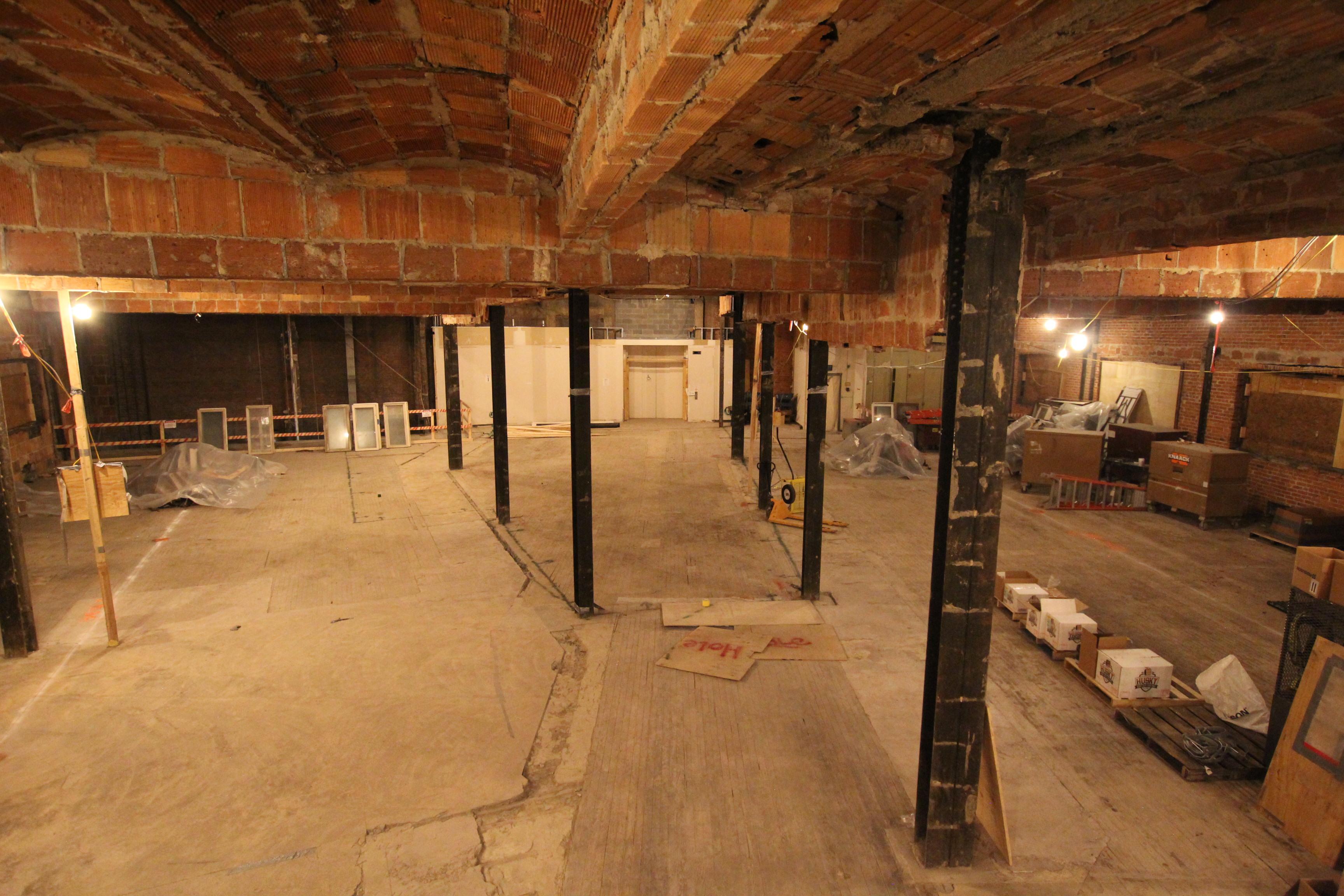 Interior of museum's 4th floor demo with exposed brick, bare floors, and metal supports.