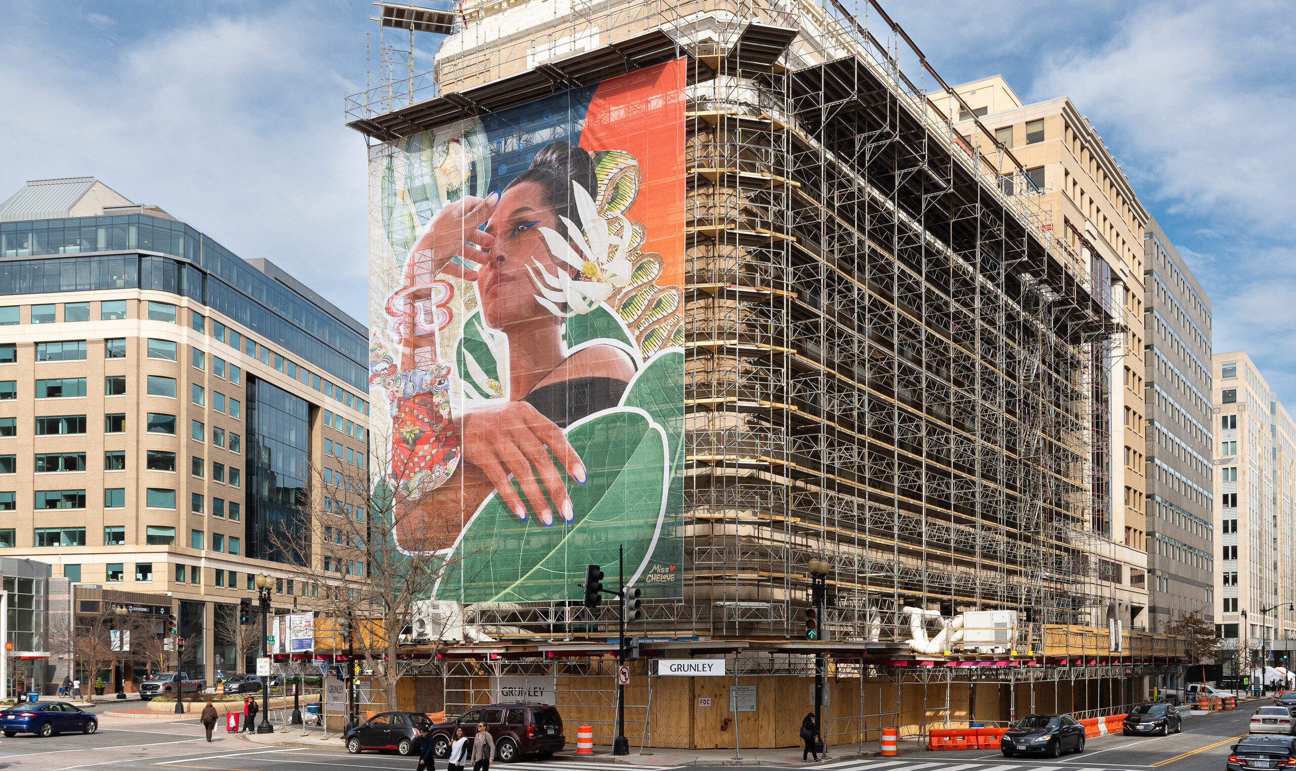 A colorful mural of a woman with flora on scaffolding on the museum building.