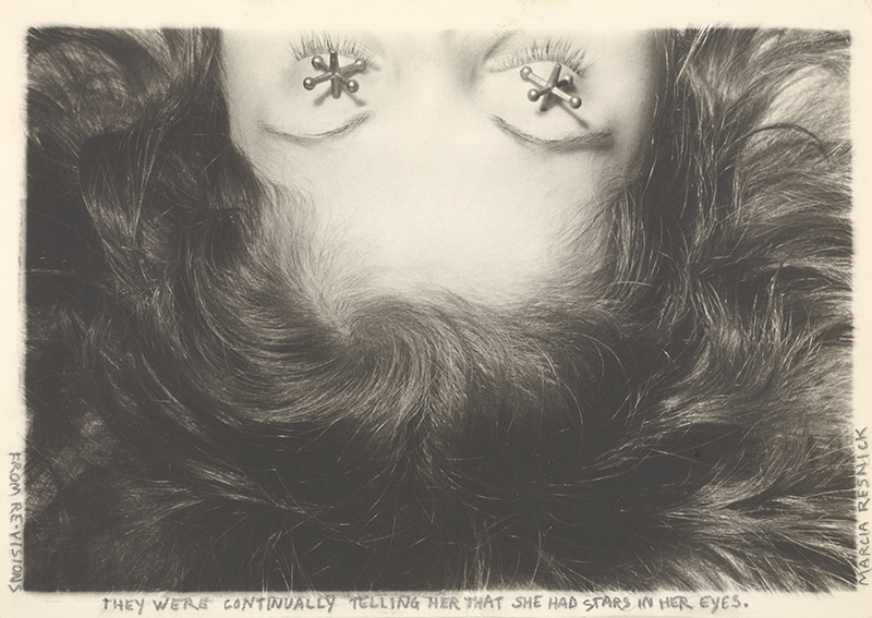 A black and white horizontal photograph shows a light-skinned woman's upside down head. It begins at her eyes, at the top, which are closed and covered with one jack over each eye. Her hair fans out around her head, taking up the entire frame in the rest of the photograph.