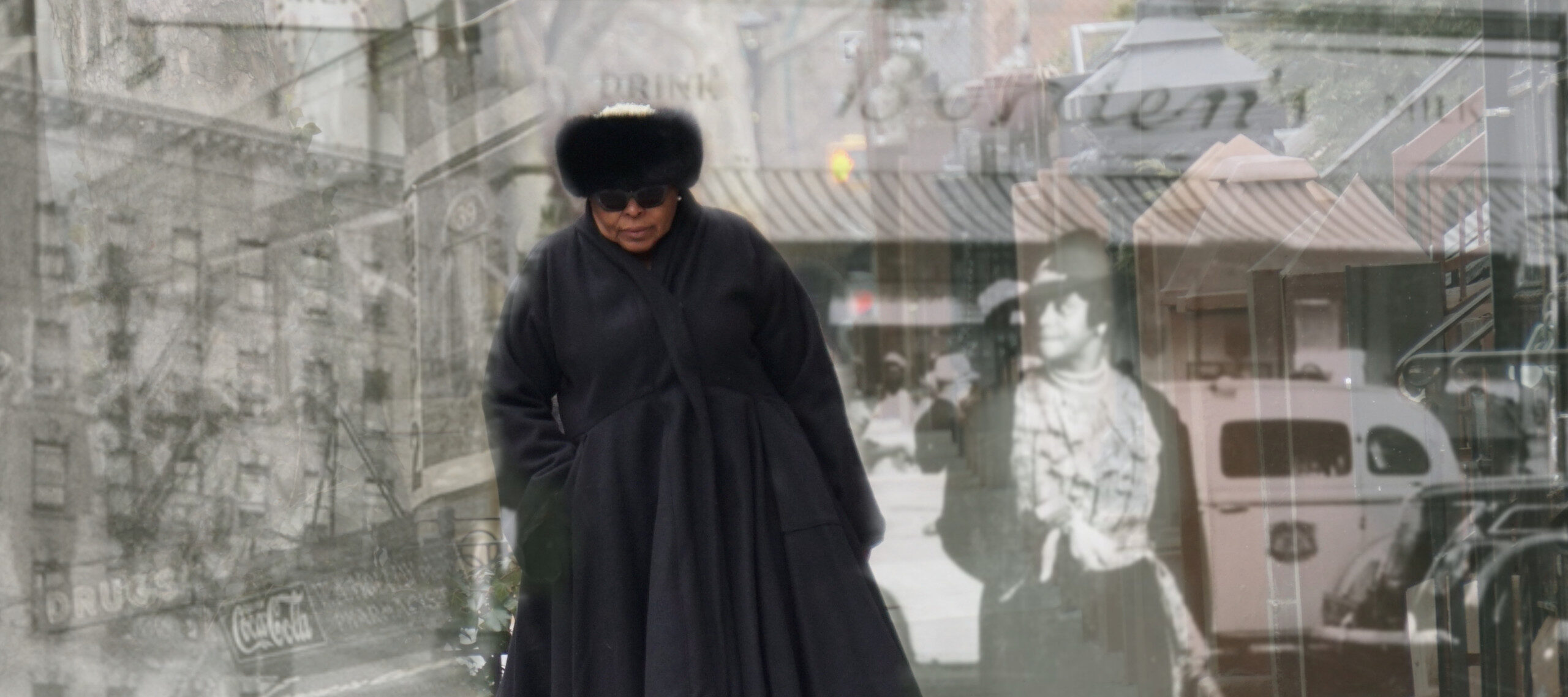 A medium-dark skinned adult woman wearing all black—a fur hat, sunglasses, boots, and a long, voluminous coat—walks on a sidewalk toward the viewer. Black and white images of people and buildings in Harlem from the early 20th century are layered over the woman.