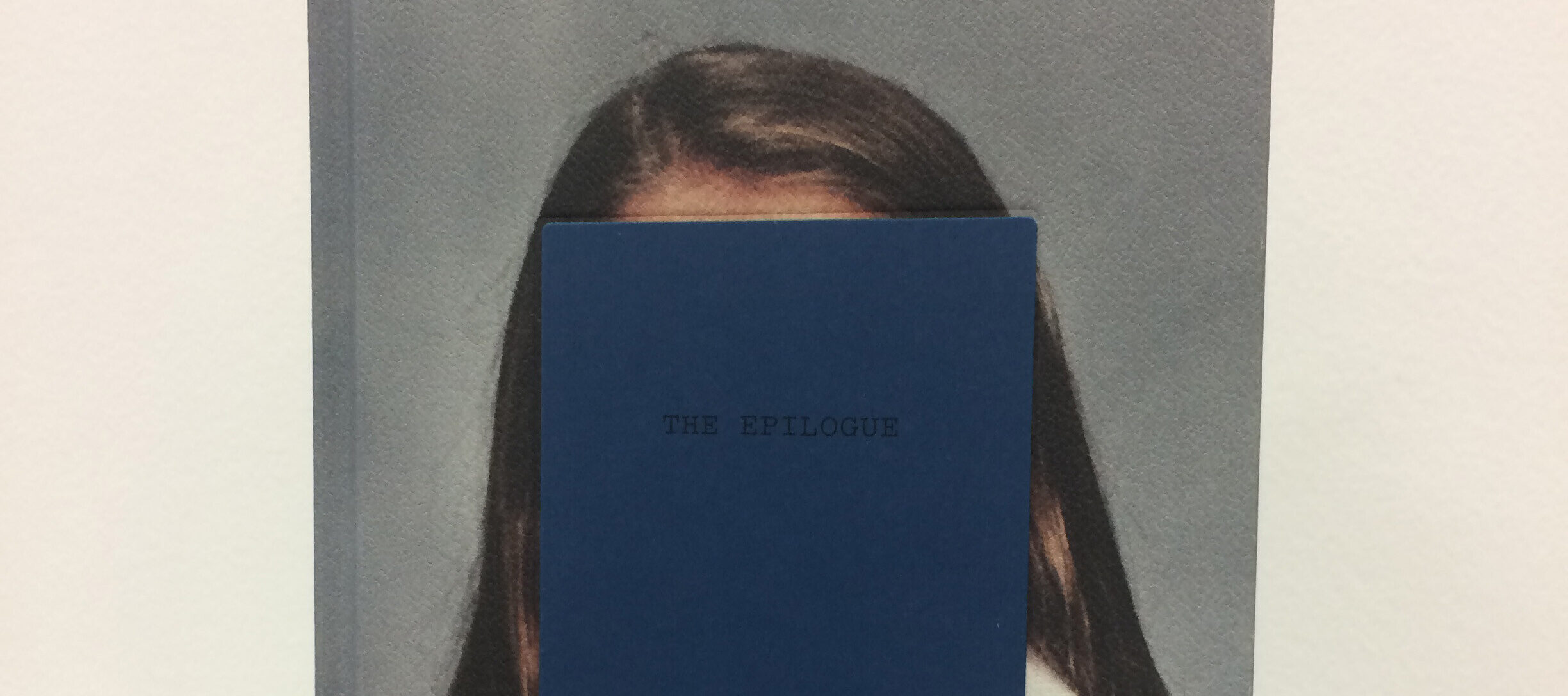 Front cover of a book featuring a color photograph portrait of a figure with long brown hair. The figure's face is obscured by rectangle on which the book's title 