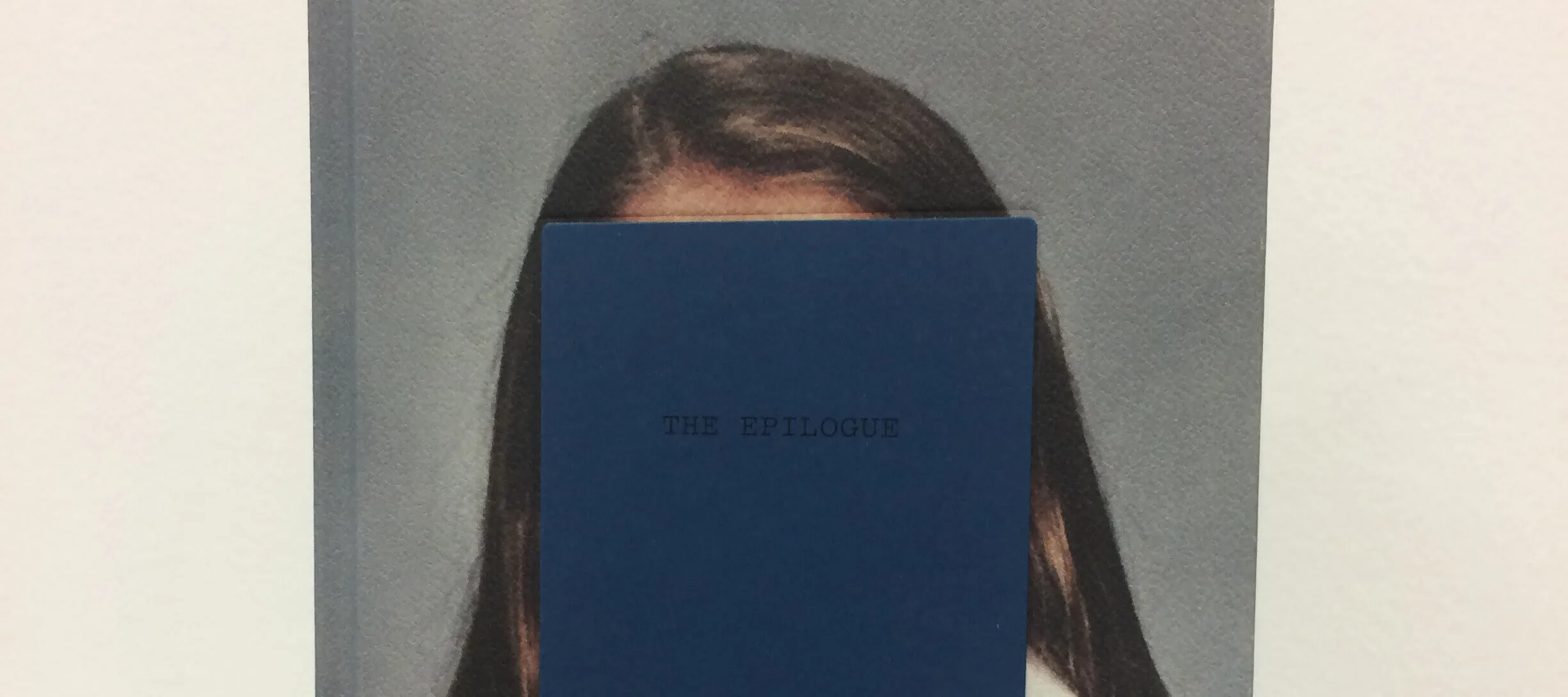 Front cover of a book featuring a color photograph portrait of a figure with long brown hair. The figure's face is obscured by rectangle on which the book's title "The Epilogue" appears all capital letters.