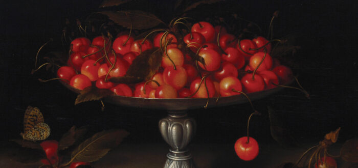 An opulent, footed silver bowl overflows with ripe cherries in front of a dramatic dark background. Additional fruits lie on the table below the bowl, and a butterfly flutters to one side.