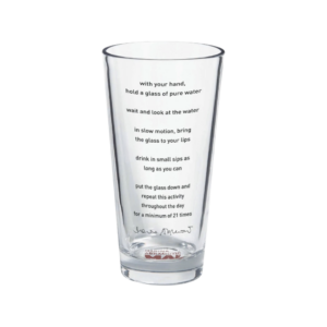 A clear pint glass with indecipherable text printed on it. 