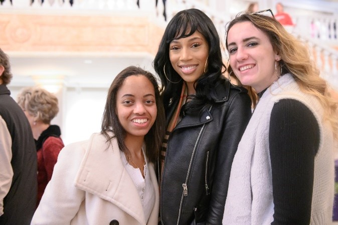 Three women stand side by side looking at the camera and smiling. 