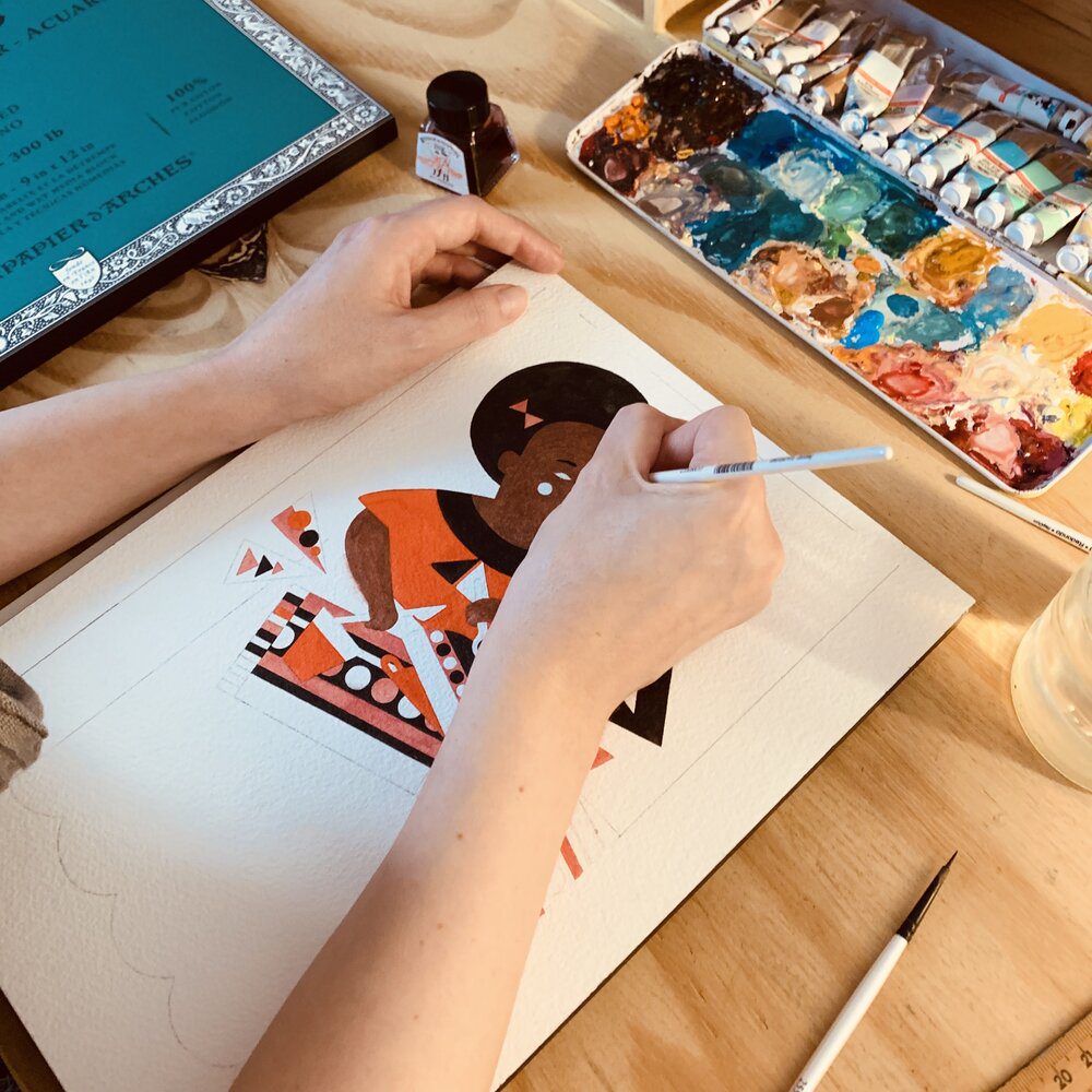 A view from above shows two hands resting on a piece of paper. The right hand is holding a brush and painting with watercolors. An unfinished artwork is visible on the paper: It shows a woman with a dark skin tone, black hair, and an orange shirt, composed of geometric shapes. 