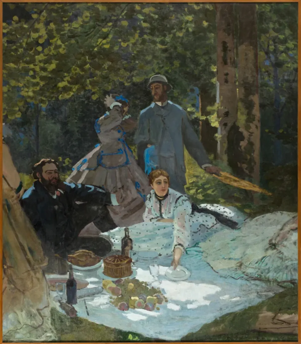 A scene of a picnic in a park on a sunny day shows four people with a light skin tone, some sitting on a picnic blanket with food, and some walking in the meadow. Their attire signals their high class, as they wear suits, hats, and long dresses in nature.