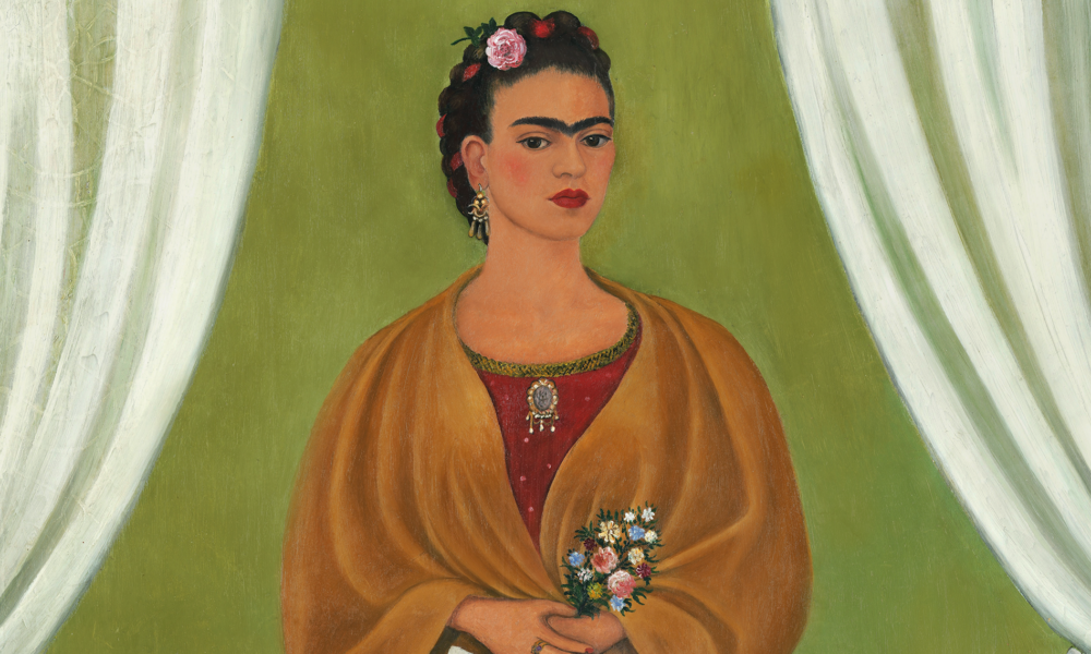 In a painted self-portrait, the artist stands in a stage-like space framed by white curtains. Beneath black hair woven with red yarn and flowers, heavy brows accent her dark-eyed gaze. Clad in a fringed, honey-toned shawl; long, pink skirt; and gold jewelry, she holds a bouquet and a handwritten letter.