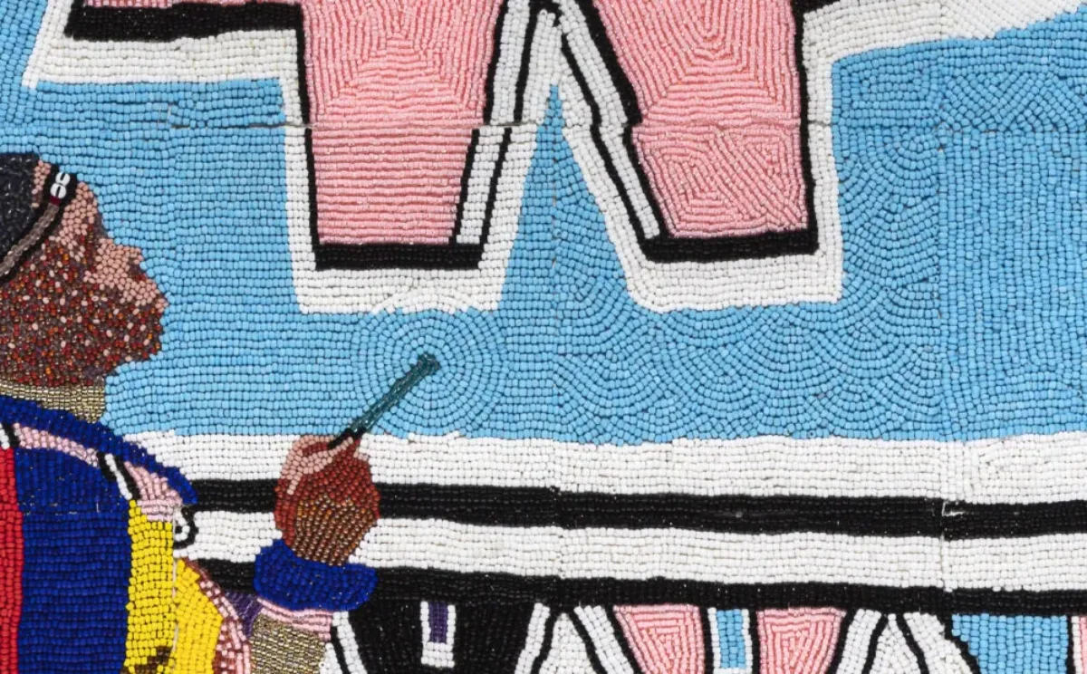 Tiny, colorful beads arranged in patterns to depict Esther Mahlangu painting a large artwork of geometric shapes in light pink and blue, black, white, yellow, and green. She is a dark-skinned adult woman wearing colorfully patterned robes.