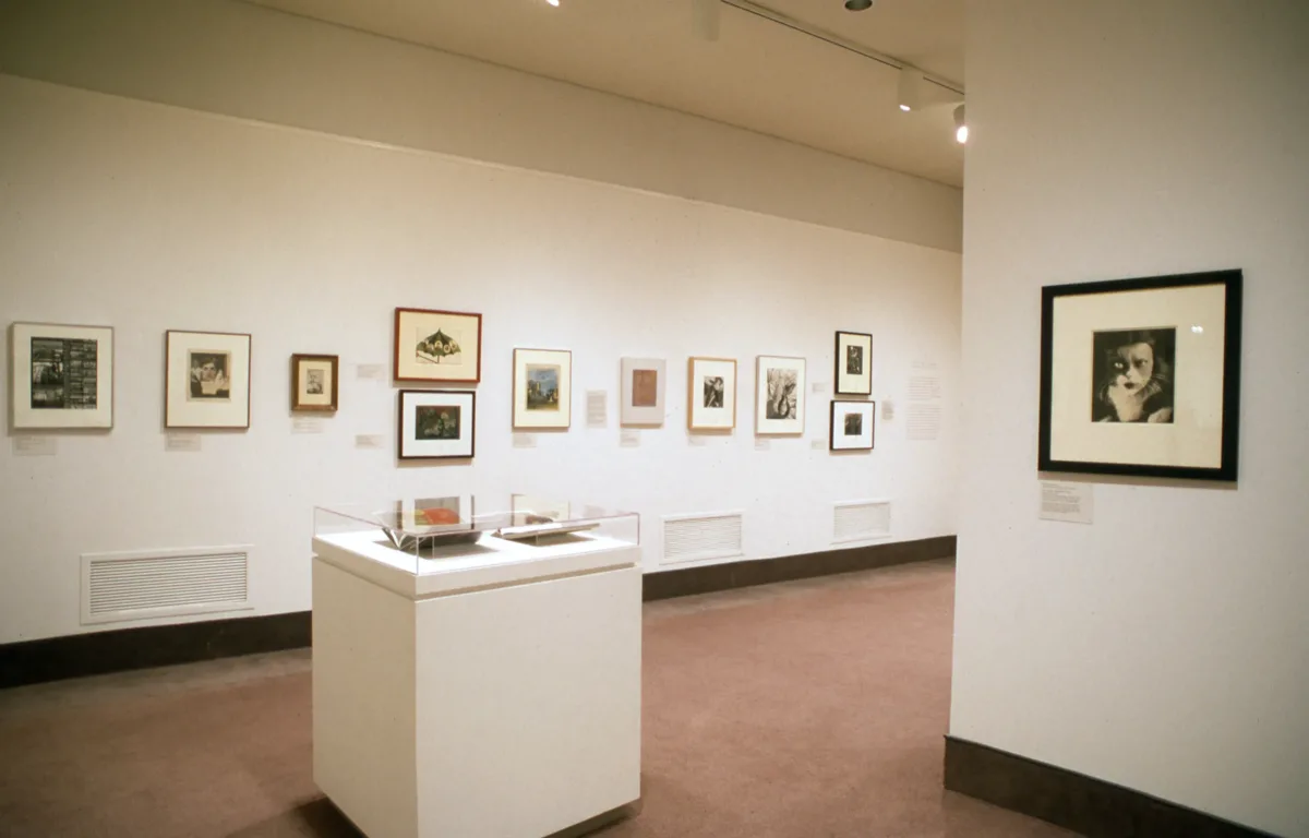 View of a gallery space covered in black-and-white photographs hanging on each wall.