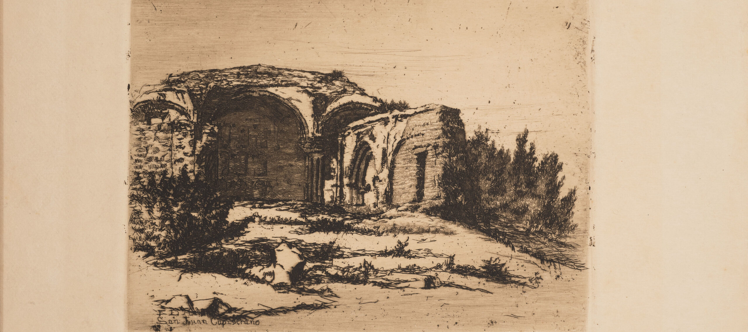 Small print of black ink on ecru paper depicting the ruins of an old Catholic mission building. The building, featuring rounded arches, crumbling facades, and exposed brick, is surrounded by scrub bushes and desert landscape.