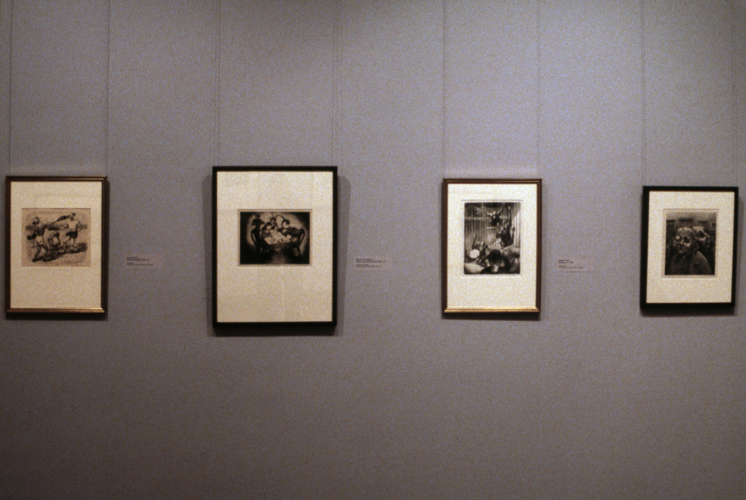 A view of a gallery space. The walls are painted gray, and several artworks are hanging on them. The artworks are black-and-white photographs.
