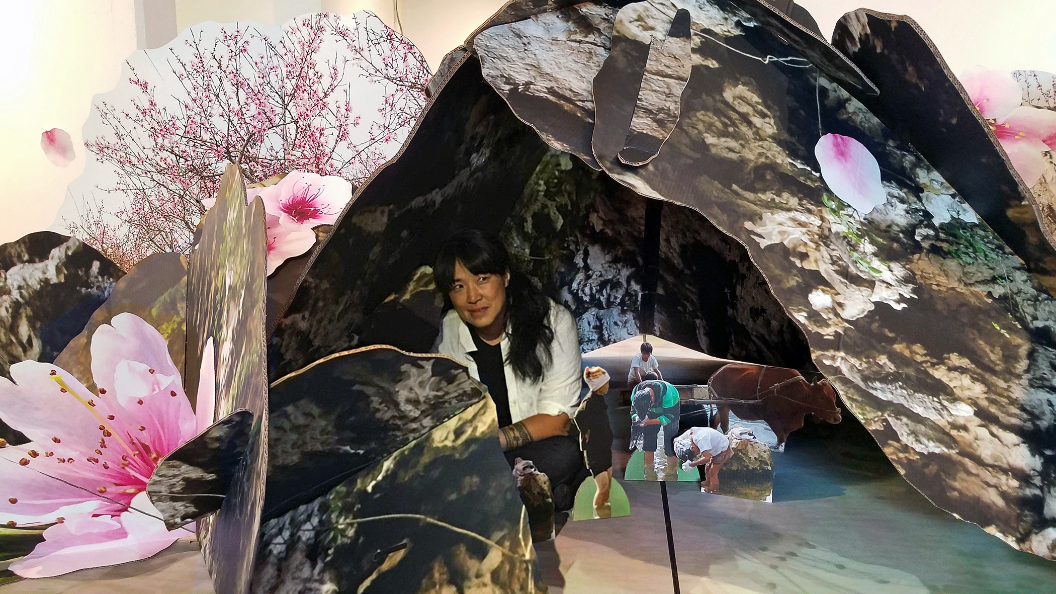 A three-dimensional photo collage of natural images creating a dome over images of five figures. The central figure is a light-skinned woman with long dark hair in a crouched position.