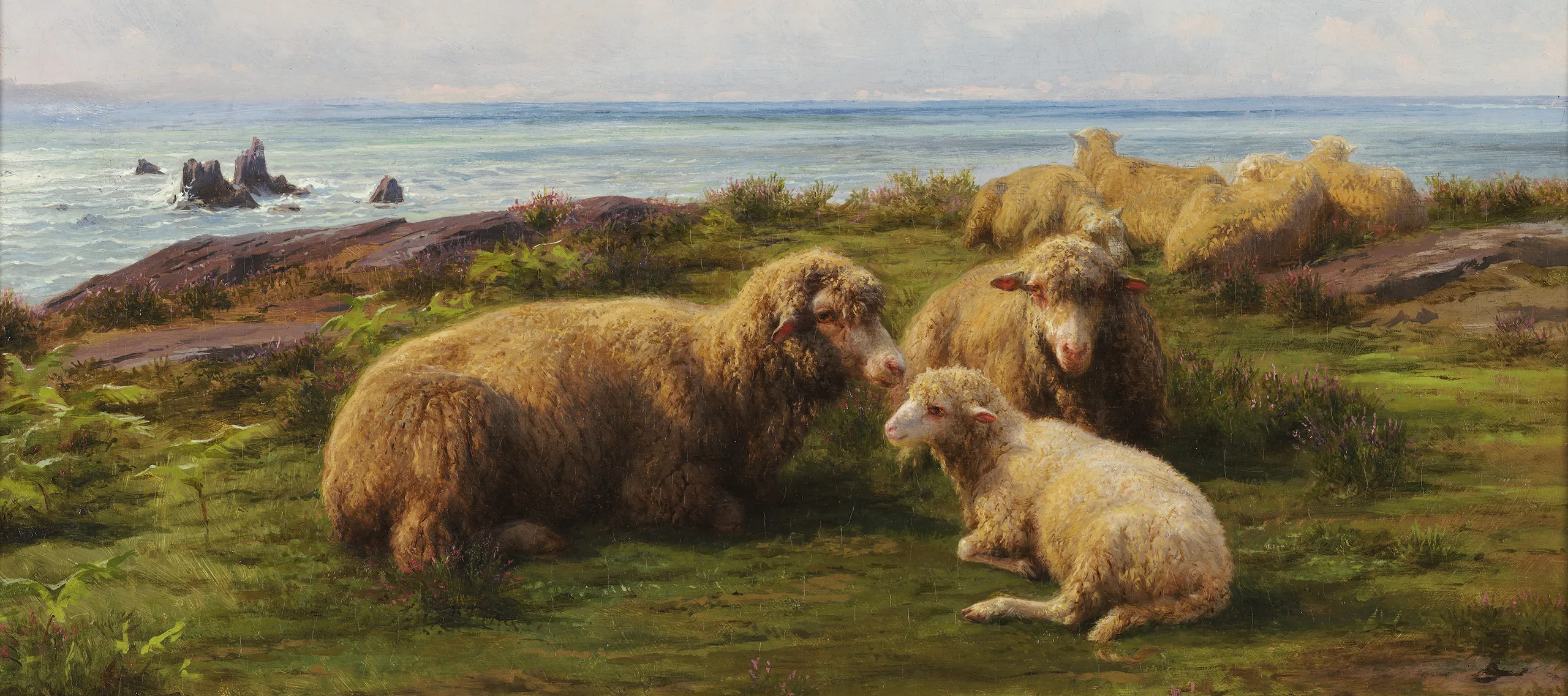 A flock of sheep rest on a green hill by the sea. In the center, two adults and a lamb lie in a group. Flat rocks are visible through the grass. The sky has rolling clouds, and a breeze is suggested by the waves crashing on rocks in the sea, which stretches to the horizon.