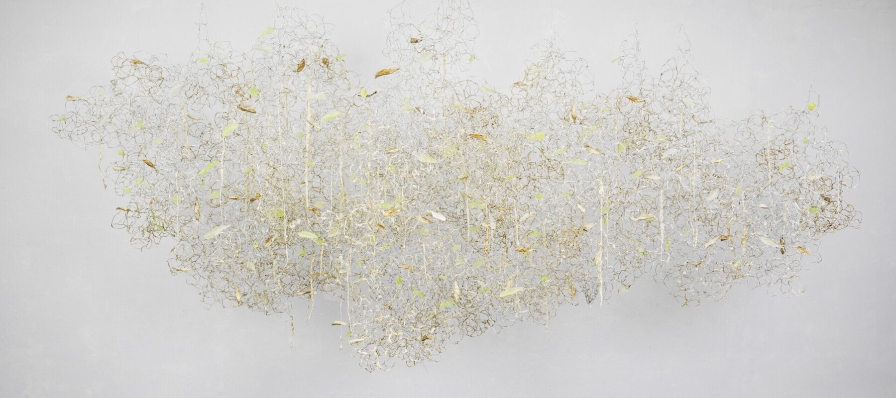 A cloud-shaped silver wire, off-white resin, and white paper pulp sculpture hung against a white wall.