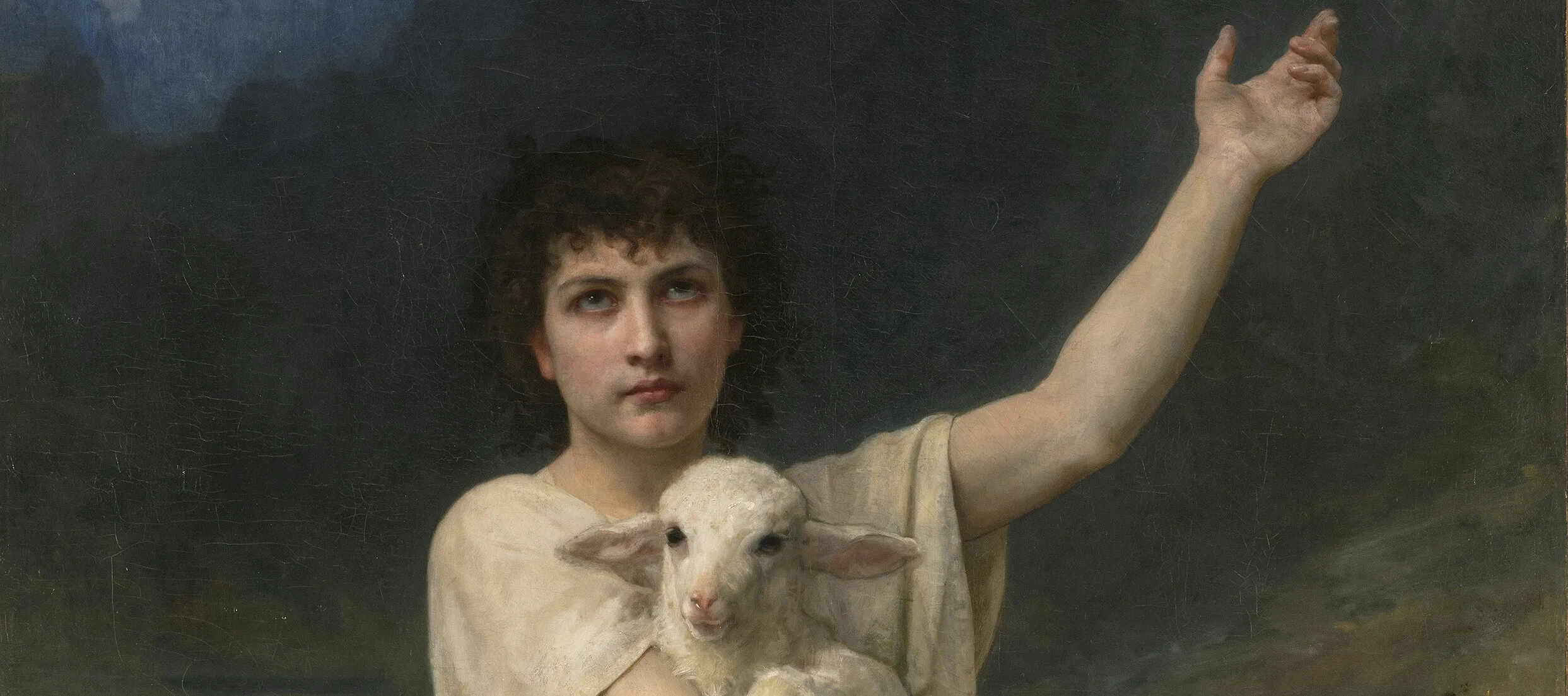 Realistic painting depicts a light-skinned young man with dark curly hair, wearing a white tunic, set before distant mountains. He is kneeling victoriously atop a fearsome dead lion, clutching a serene lamb his right arm and gesturing heavenward with his left arm.