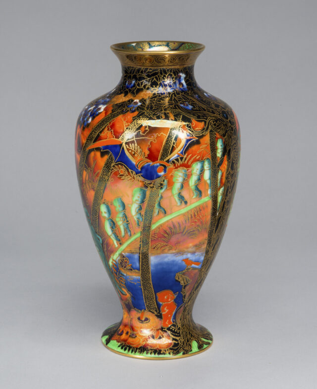 A shiny vase with vibrant oranges, blues, greens, and gold accents with wide shoulders and a narrow neck, edged in gold.