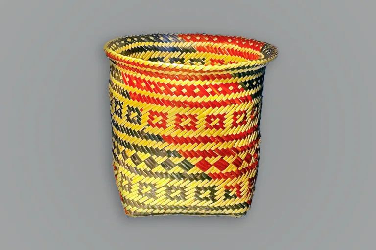 A light-colored woven basket with black horizontal stripes and geometric patterns.