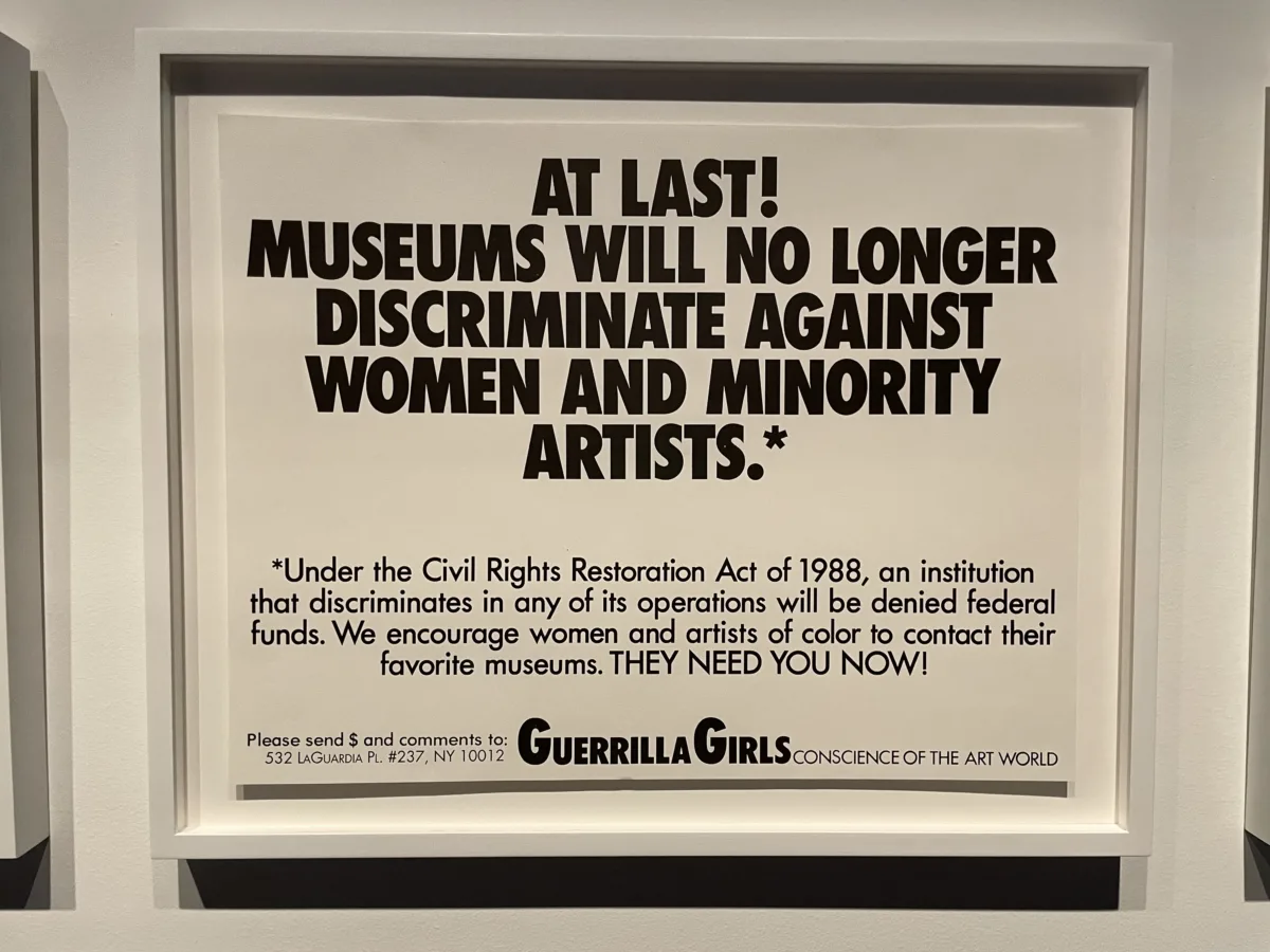 Art print with black text on a white background. Large text at the top reads, "At last! Museums will no longer discriminate against women and minority artists.*" Smaller text below reads, "Under the Civil Rights Restoration Act of 1988, an institution that discriminates in any of its operations will be denied federal funds. We encourage women and artists of color to contact their favorite museums. They need you now!" At the bottom of the print reads "Please send $ and comments to: 532 LaGuardia Pl. #237, NY 10012" "Guerrilla Girls Conscience of the art world"