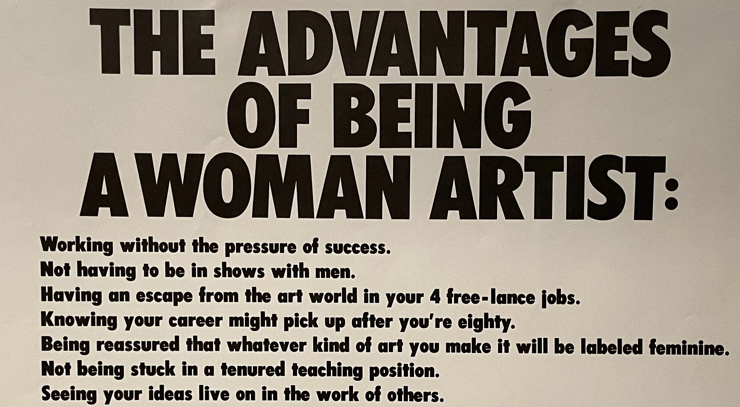 Art print with black text on a white background. Large text at the top reads, "The advantages of being a woman artist:" A list below reads, "Working without the pressure of success. Not having to be in shows with men. Having an escape from the art world in your 4 free-lance jobs. Knowing your career might pick up after you're eighty. Being reassured that whatever kind of art you make it will be labeled feminine. Not being stuck in a tenured teaching position. Seeing your ideas live on in the work of others. Having the opportunity to choose between career and motherhood. Not having to choke on those big cigars or paint in Italian suits. Having more time to work after your mate dumps you for someone younger. Being included in revised versions of art history. Not having to undergo the embarrassment of being called a genius. Getting your picture in the art magazines wearing a gorilla suit." At the bottom of the print reads "Please send $ and comments to: Box 1056 Cooper Sta. NY, NY 10276" "Guerrilla Girls Conscience of the art world"