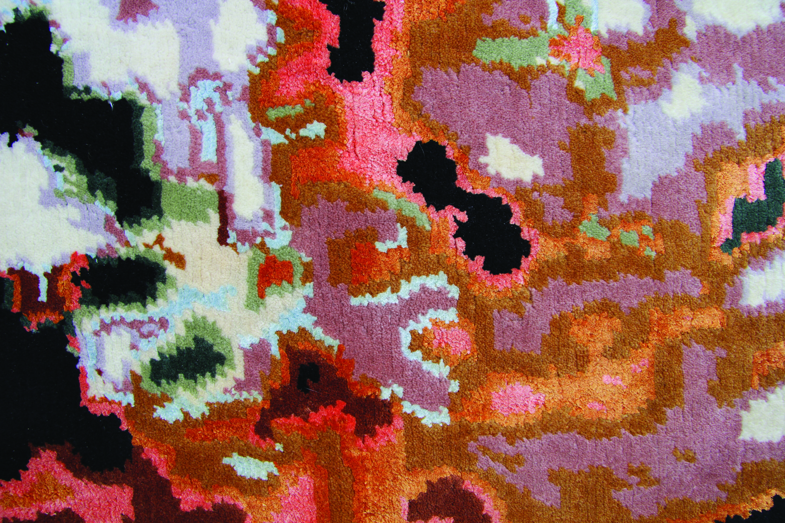 An up-close image of a plush tapestry woven with wool and silk. The colorful, abstract pattern on the tapestry looks like a pixelated image. Its organic shapes resemble a satellite image of the weather, but the pattern is woven in peaches, oranges, blacks, and very light blues.