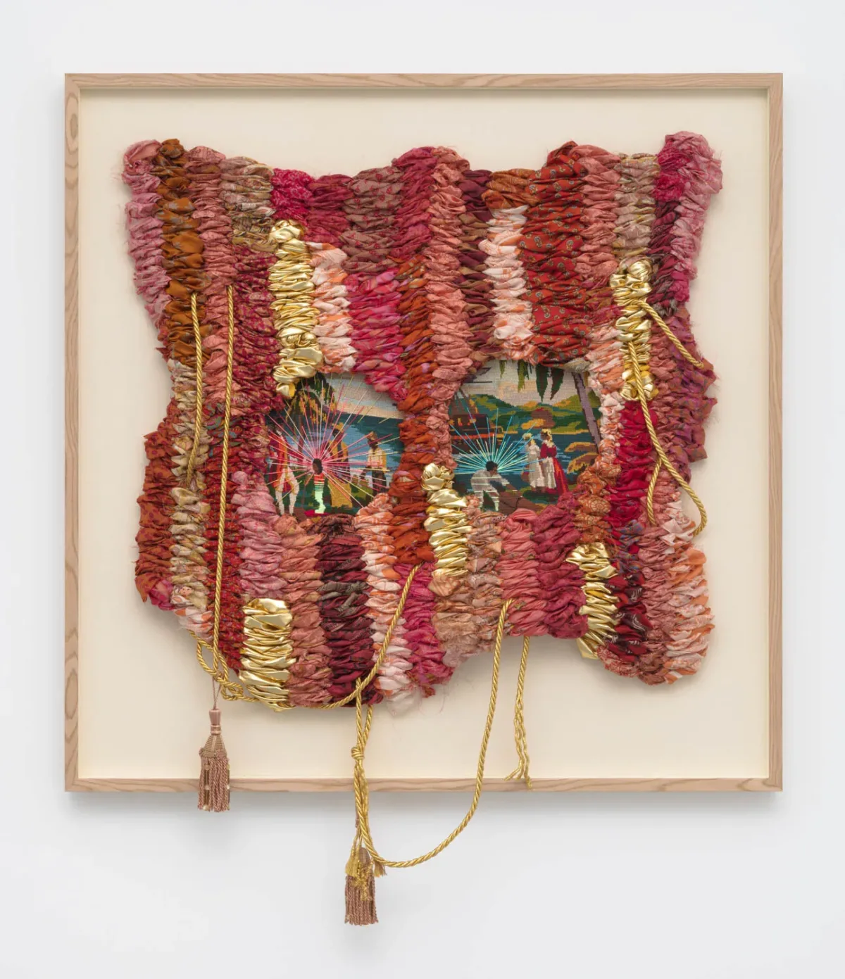 A vintage needlepoint depicting men and women with dark skin tone in a pastoral landscape. Colorful threads are sewn over the original needlepoint. Red, green, orange and pink woven fabric surrounds the needlepoint.