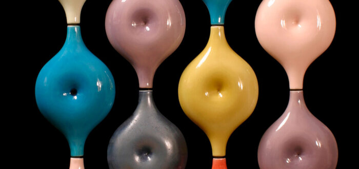Round shapes with dimples in the middle that resemble the belly button from the human body in candy-colored glazes that are stacked in four vertical rows of to create S-shaped lines.