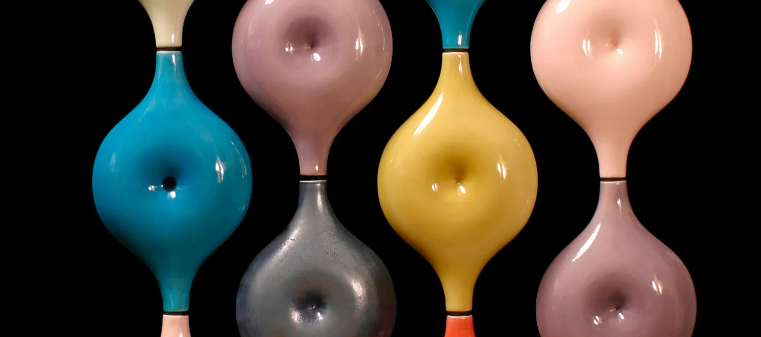 Round shapes with dimples in the middle that resemble the belly button from the human body in candy-colored glazes that are stacked in four vertical rows of to create S-shaped lines.