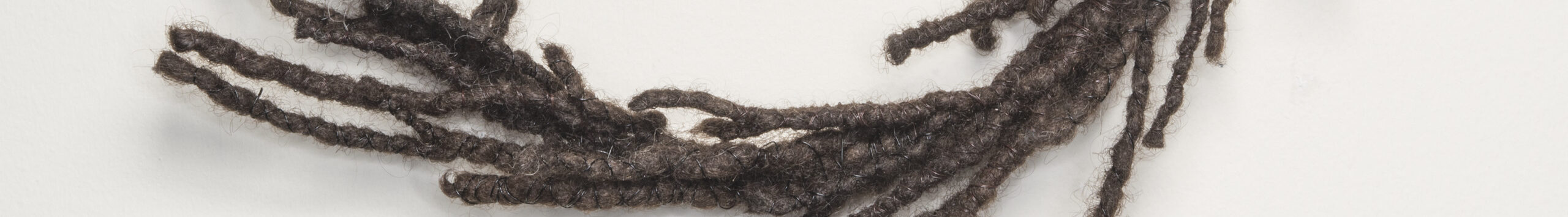 A circular wreath made of dark, tightly coiled hair with strands escaping and resembling laurels.