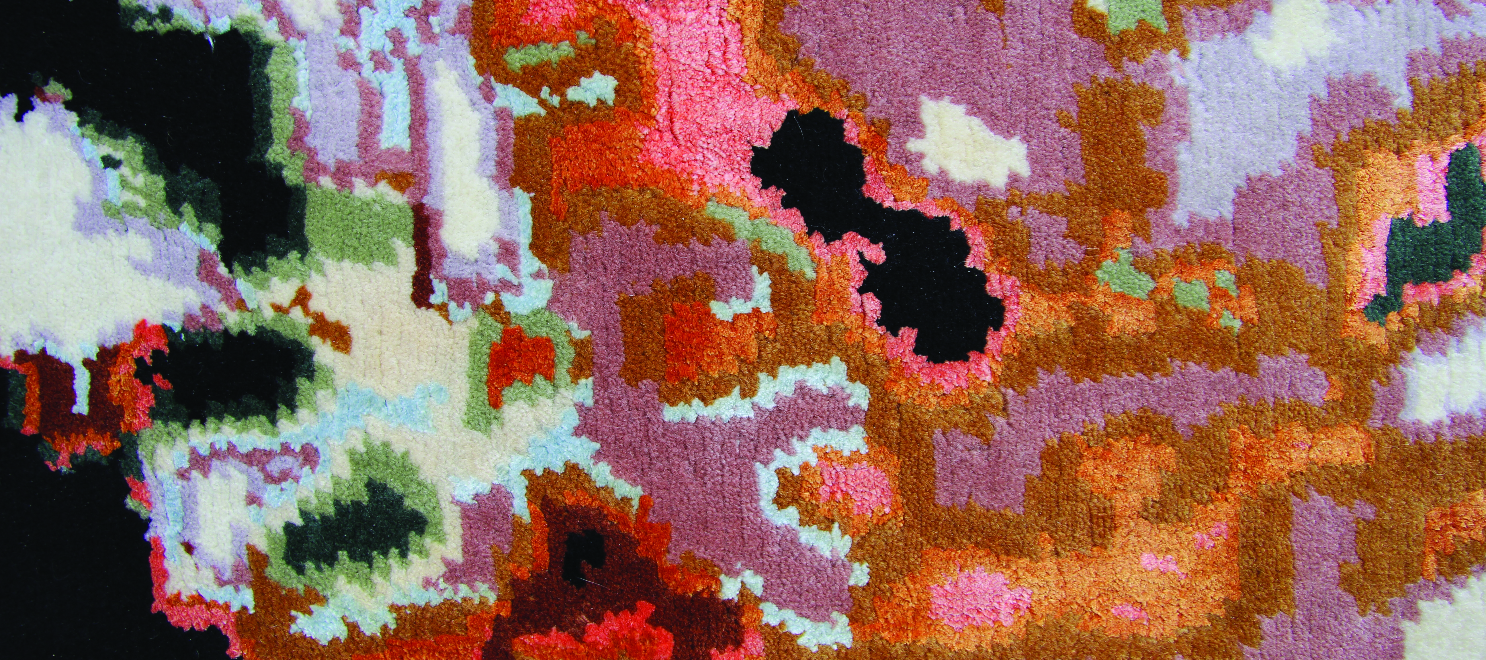 An up-close image of a plush tapestry woven with wool and silk. The colorful, abstract pattern on the tapestry looks like a pixelated image. Its organic shapes resemble a satellite image of the weather, but the pattern is woven in peaches, oranges, blacks, and very light blues.