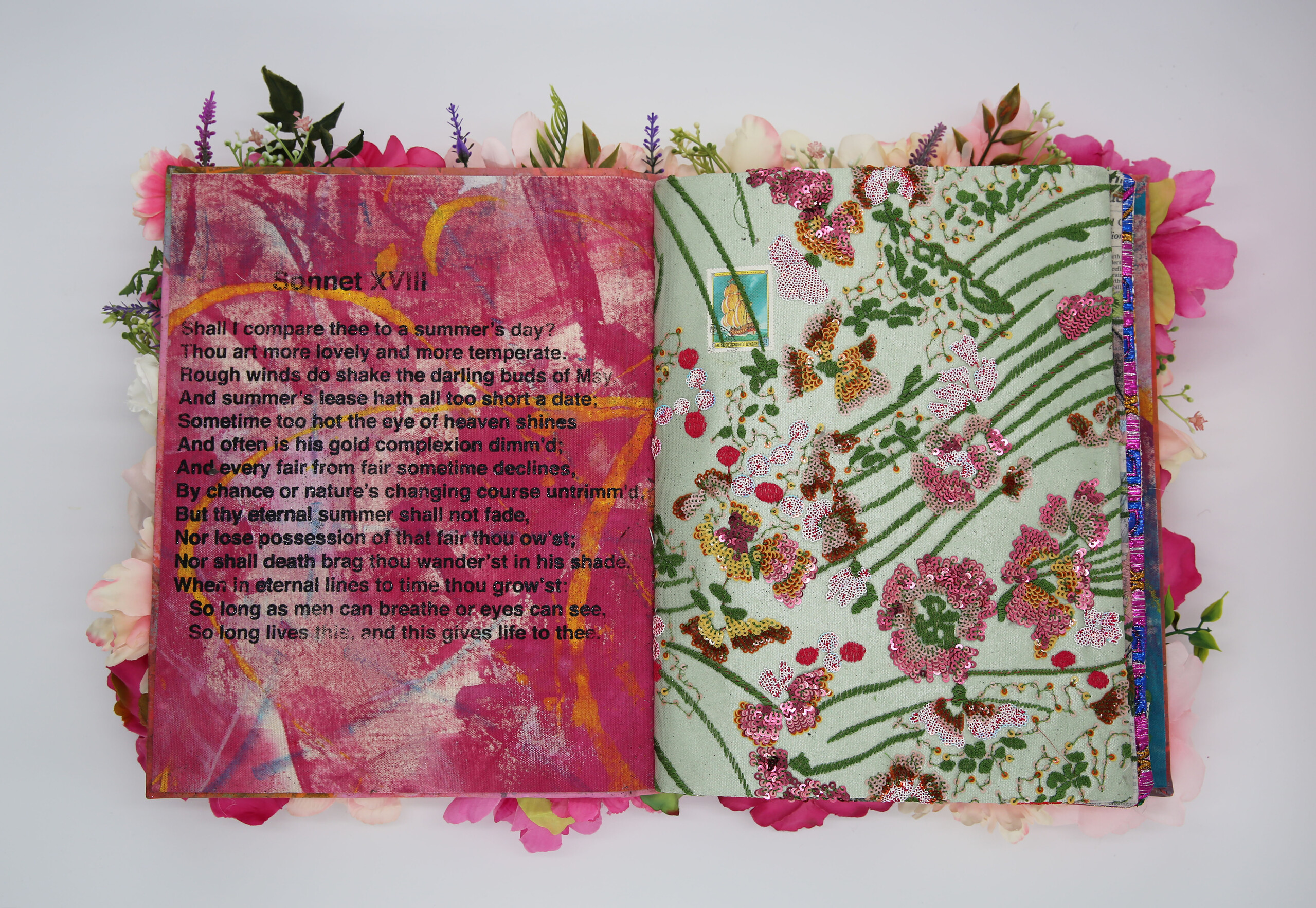 A photo of an artist's book, open in the middle. The left page displays Shakespeare's Sonnet XVII, and is painted in pink and yellow streaks. The right page has embroidered and sequined flowers and leaves.