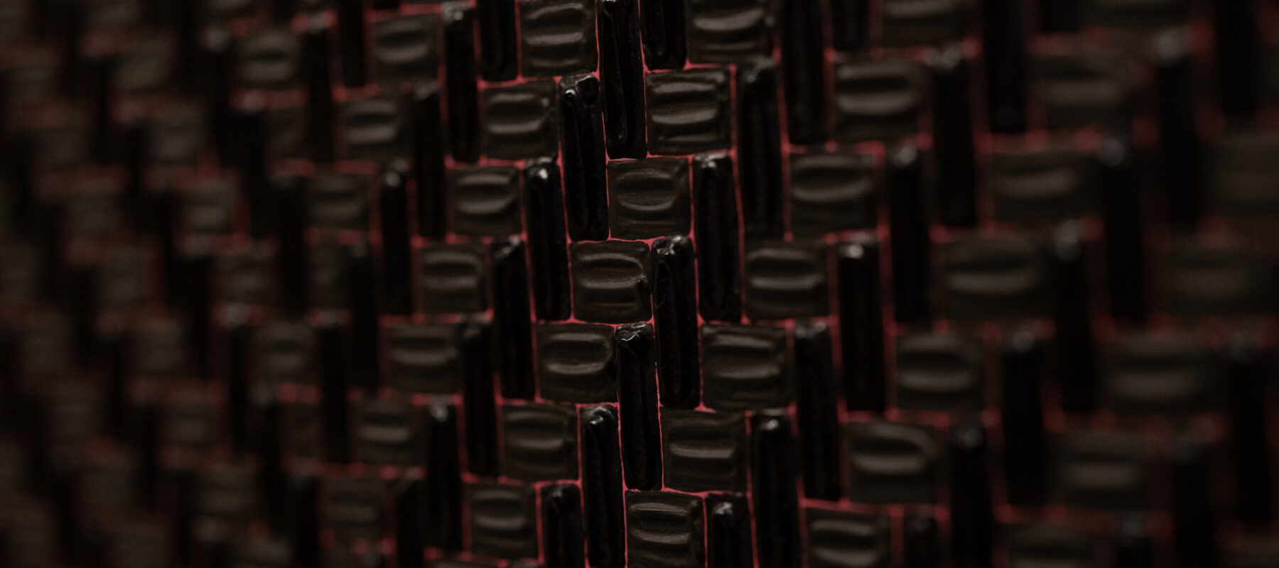 Close-up detail of a larger abstract artwork features thick black paint meticulously applied in small neat rectangles alternating orientation to form a grid. There is a minuscule amount of space between the tiles that allows a pink background to show through.