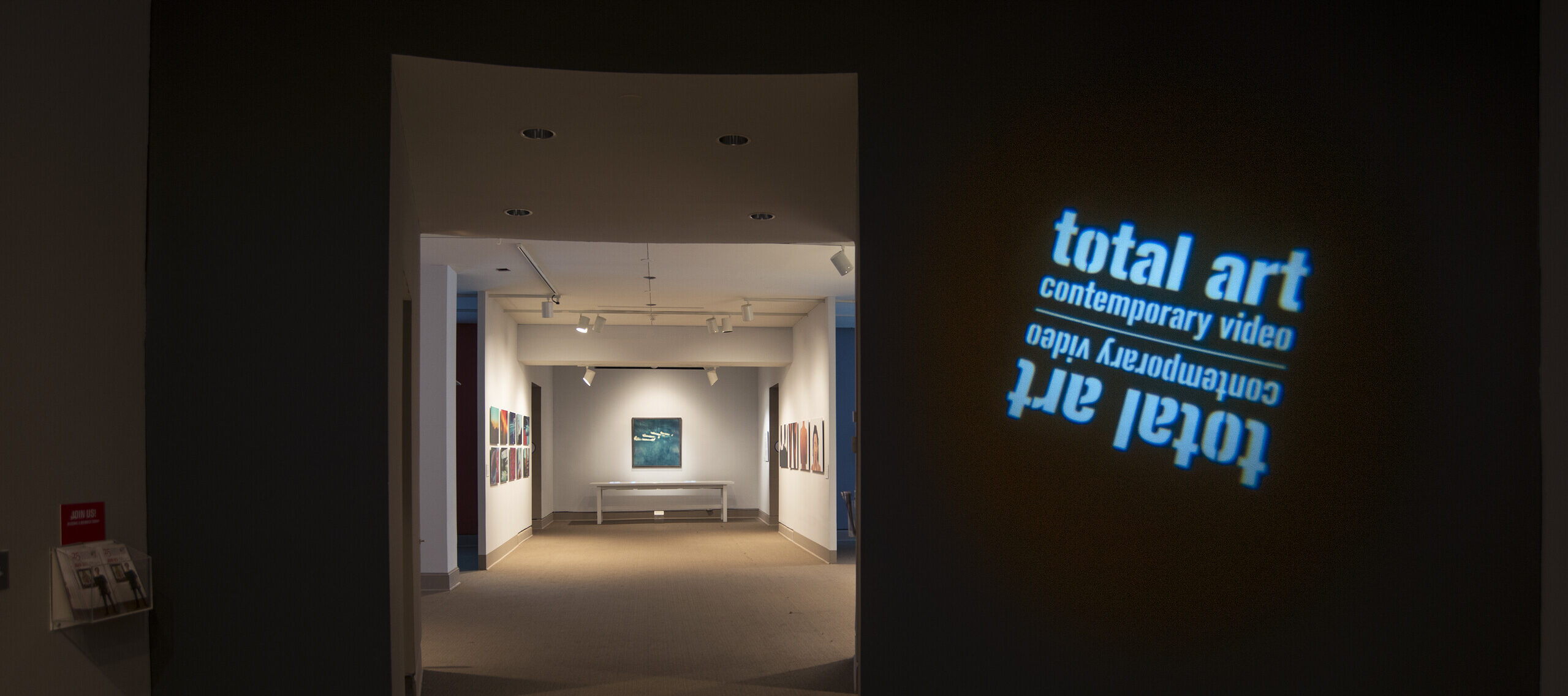 View of a gallery space. In a dark room, the title of the exhibition, 