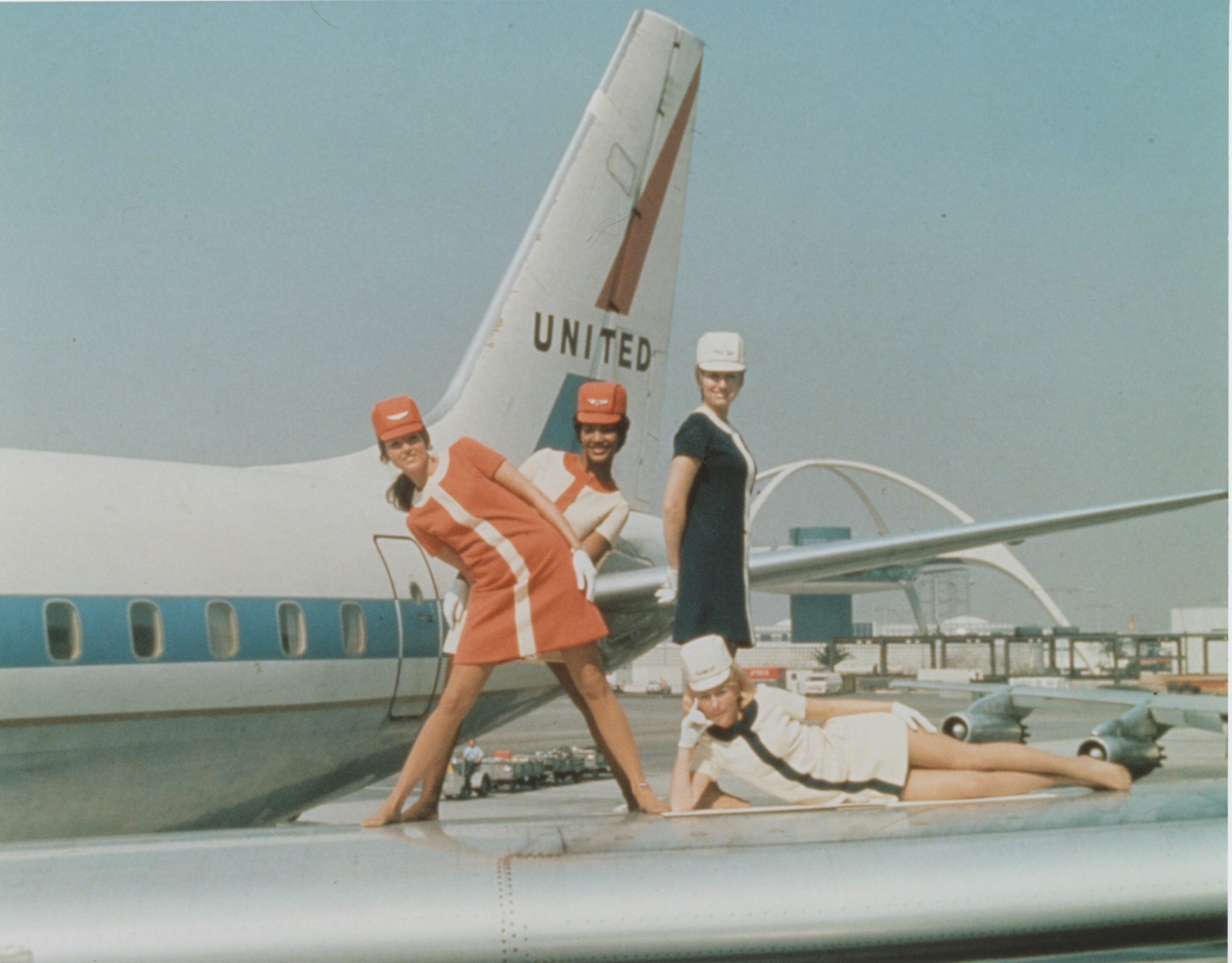 Four women flight attendants pose on the wings of a United Airlines plane in the 1960s.