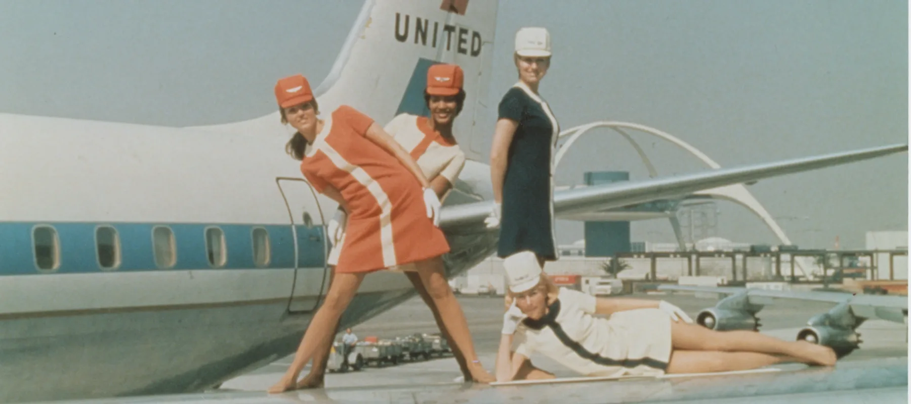 Four women flight attendants pose on the wings of a United Airlines plane in the 1960s.