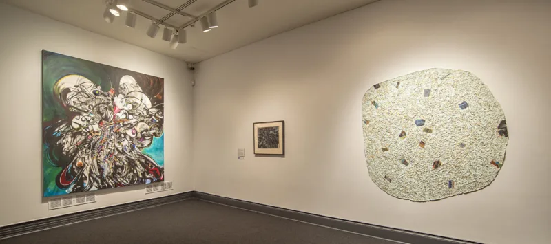 An installation view of several abstract artworks hung on a gallery wall.