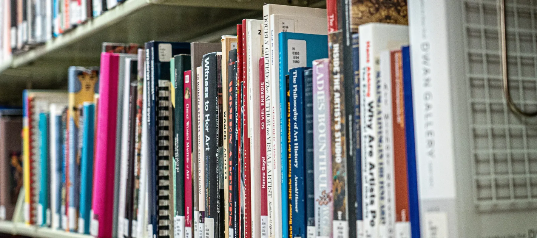 A bookshelf packed with colorful books about women artists.