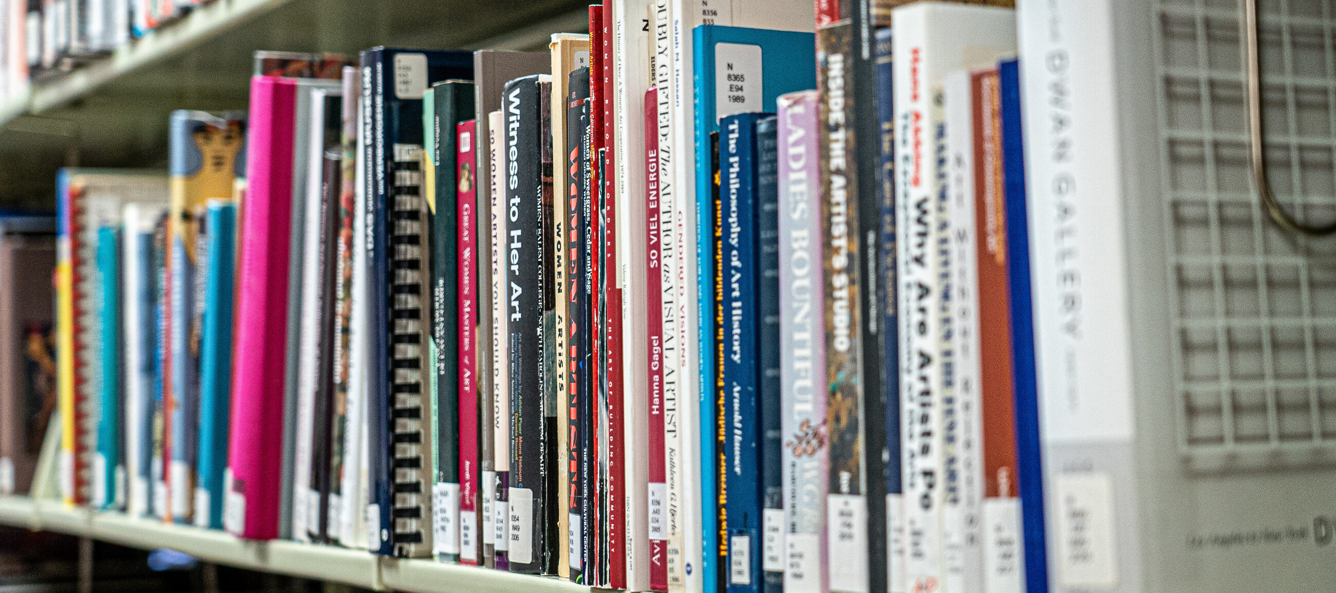 A bookshelf packed with colorful books about women artists.