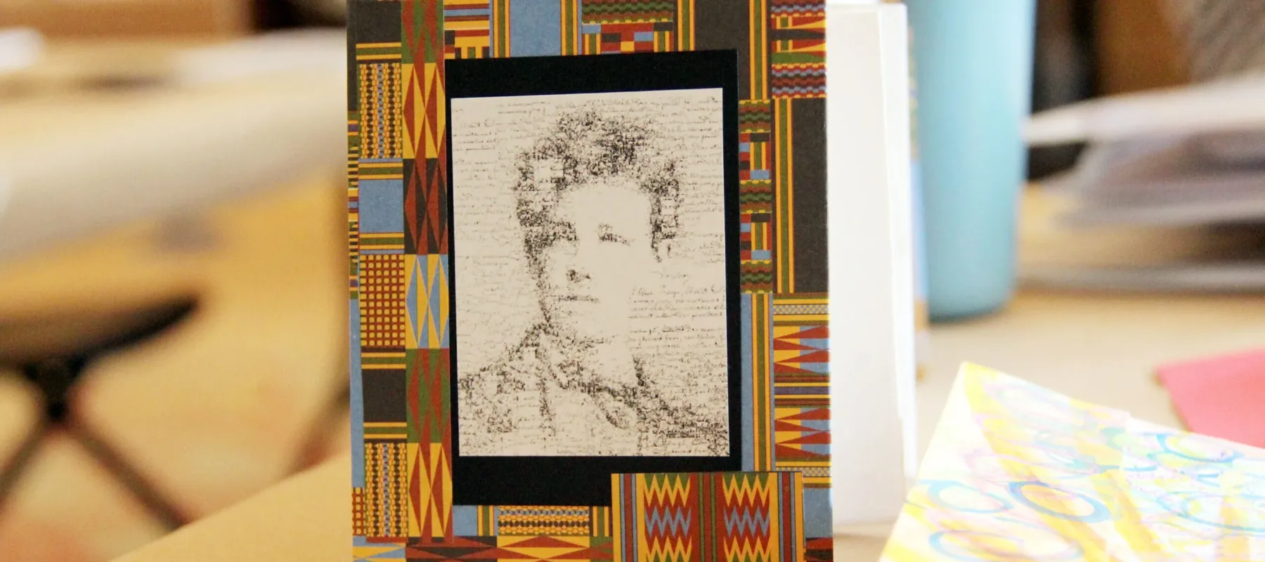 Pocket accordion book with black-and-white portrait surrounded by a paper border of multicolor geometric shapes that resemble textiles.