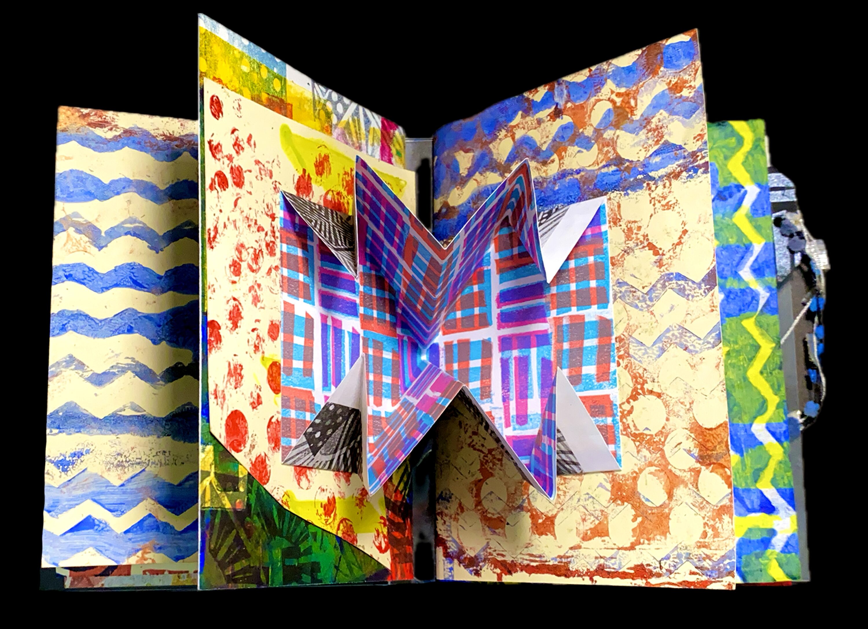 An open open book with a pop-up element in the center spread. Several pages of the book are visible, and each has a different, brightly patterned design printed on it.