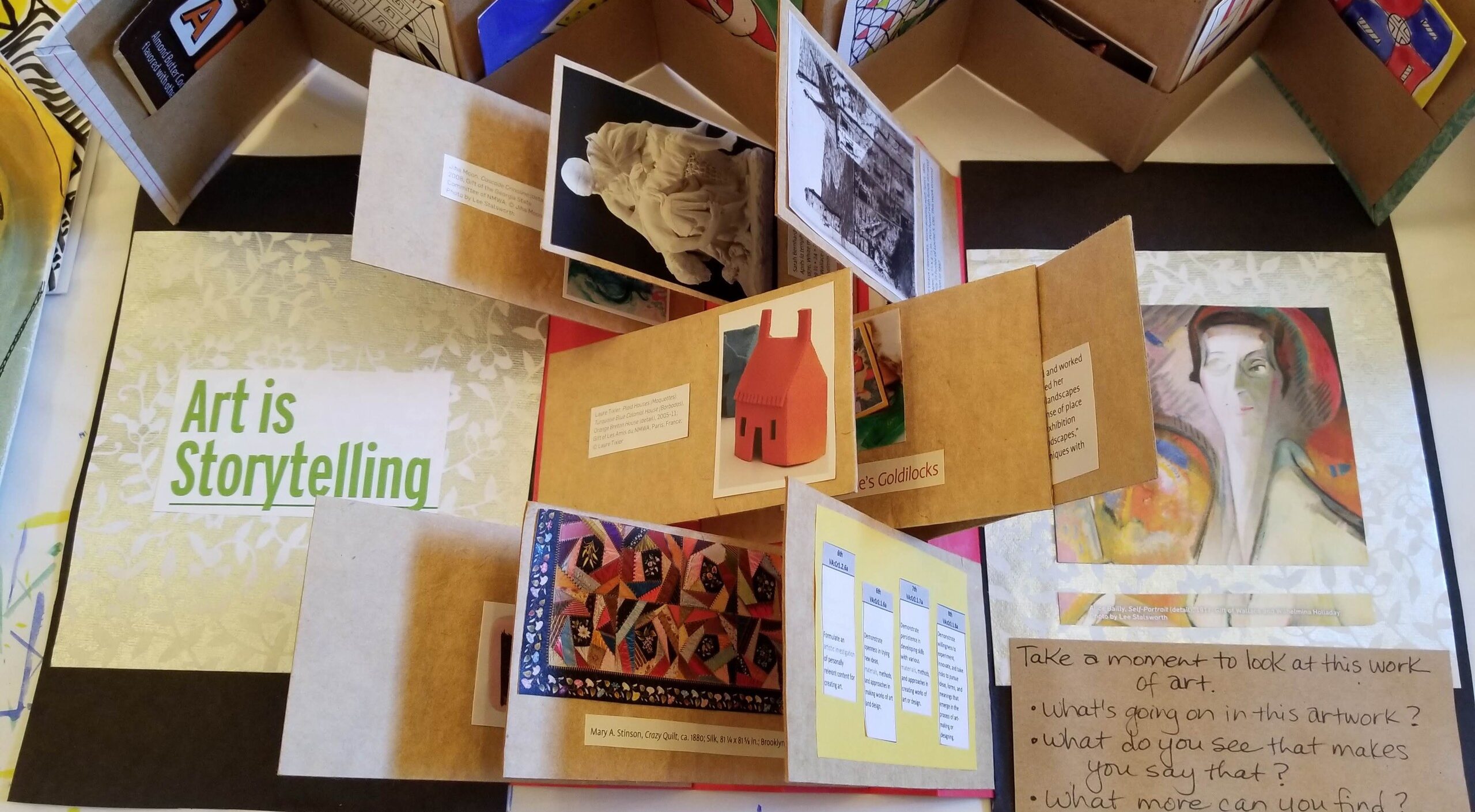 A birds-eyed view of a variety of artists books showing a variety of folded paper and works of art.