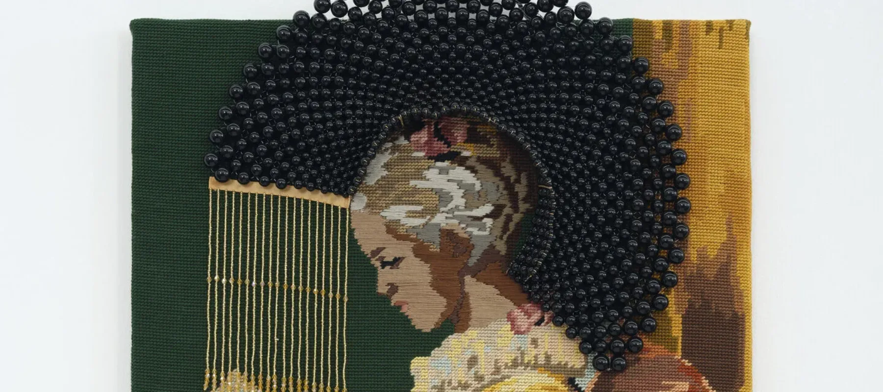 A needlepoint depicting, in profile, a seated, young girl with medium skin tone and dark hair in a yellow dress reading a book. A halo of black beads surrounds her bowed head.