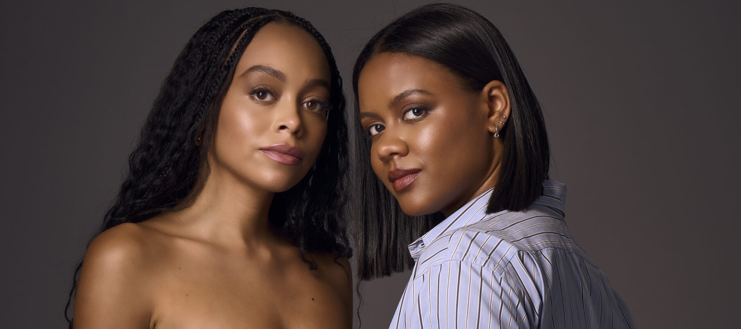 Two women with medium-dark colored skin and dark brown hair stand next to each other.