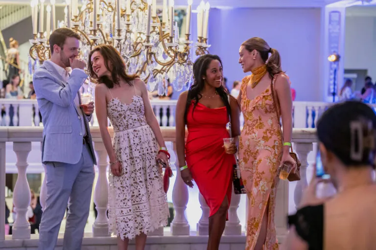 A man and three women all in semiformal attire talk to each other as they pose for a picture.