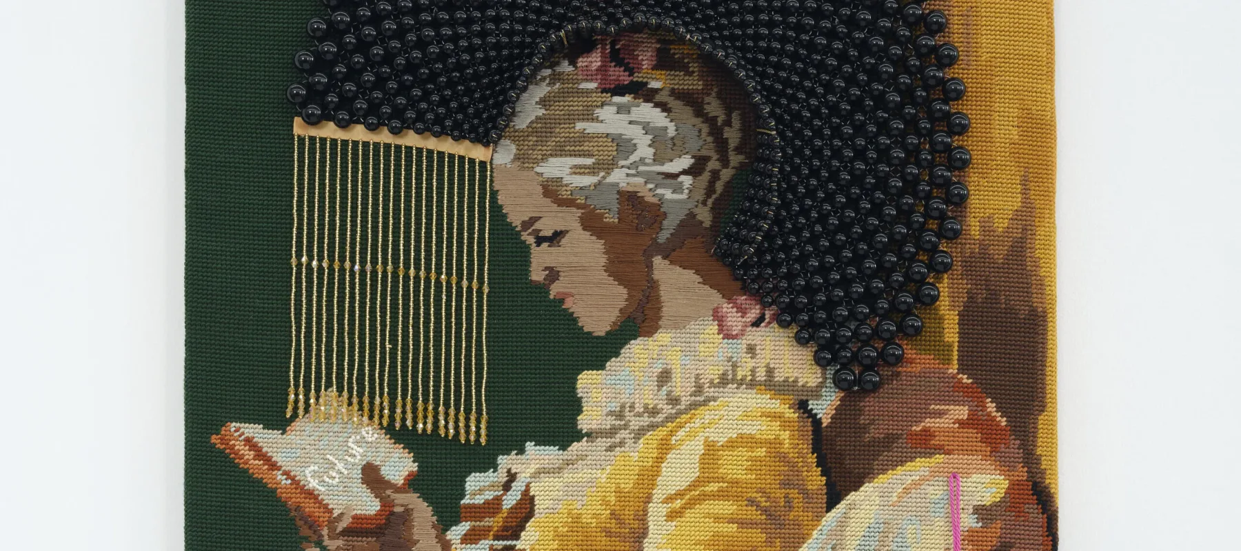 A needlepoint depicting, in profile, a seated, young girl with medium skin tone and dark hair in a yellow dress reading a book. A halo of black beads surrounds her bowed head.