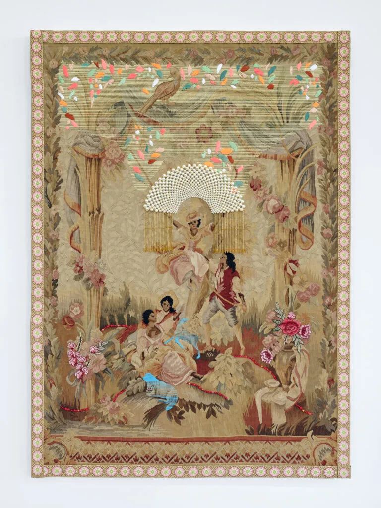 A vintage tapestry depicting three women and one man in a pastoral scene. One woman sits atop a swing while the others sit beneath her. The man holds the rope of the swing. Bright thread and beads are sewn over the original tapestry, and all four figures skin and hair have been darkened with brown and black thread.