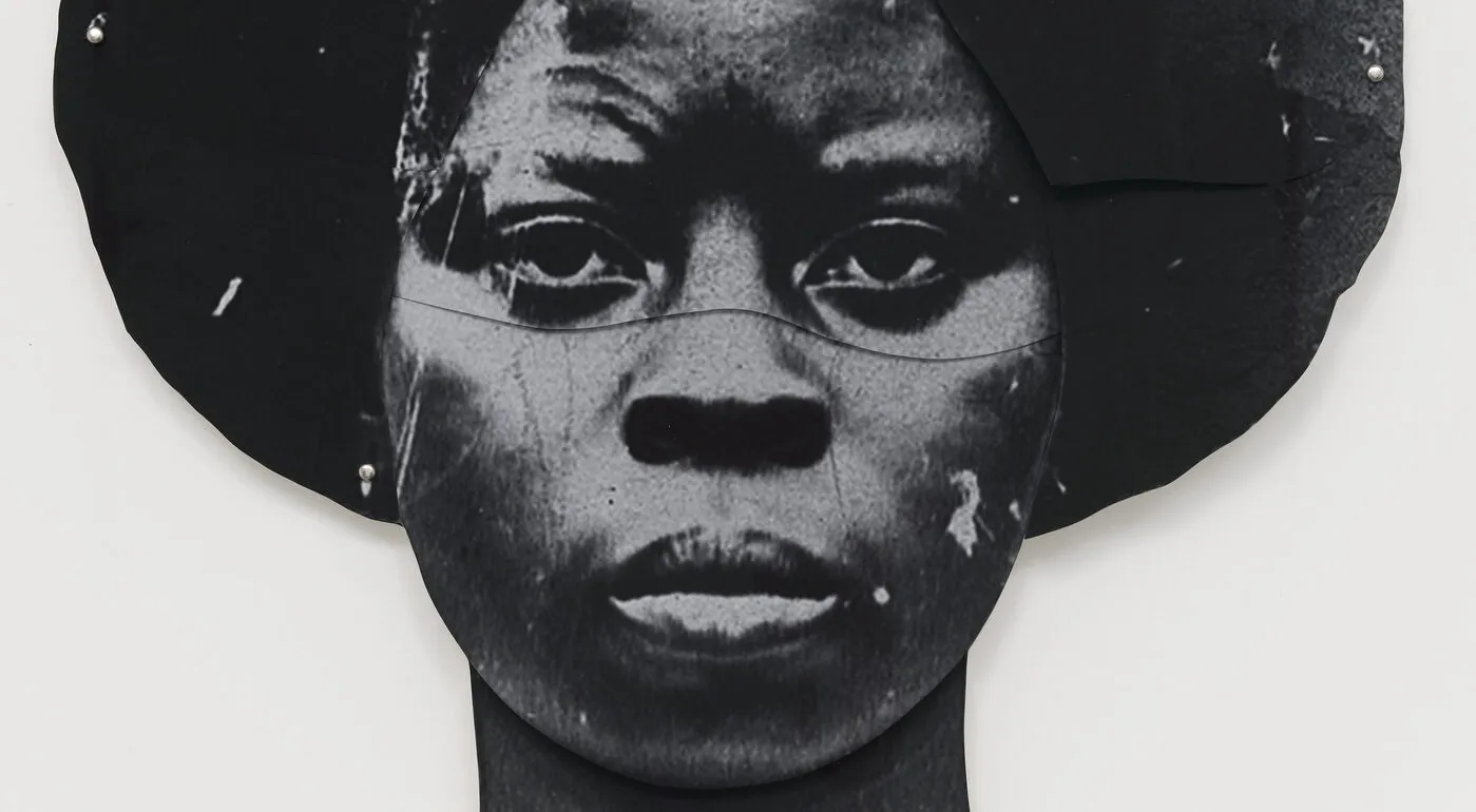 A black-and-white artwork features a dark-skinned woman's duplicated head, one facing the viewer straight on and the other upside down. The faces are stylized and abstract, with a textured appearance, set against a plain white background.