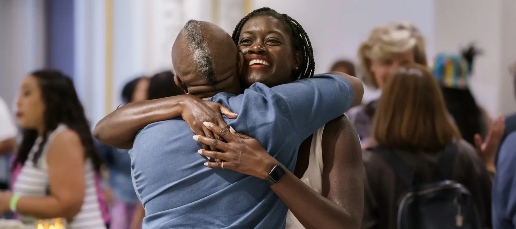 Two people hug each other, smiling