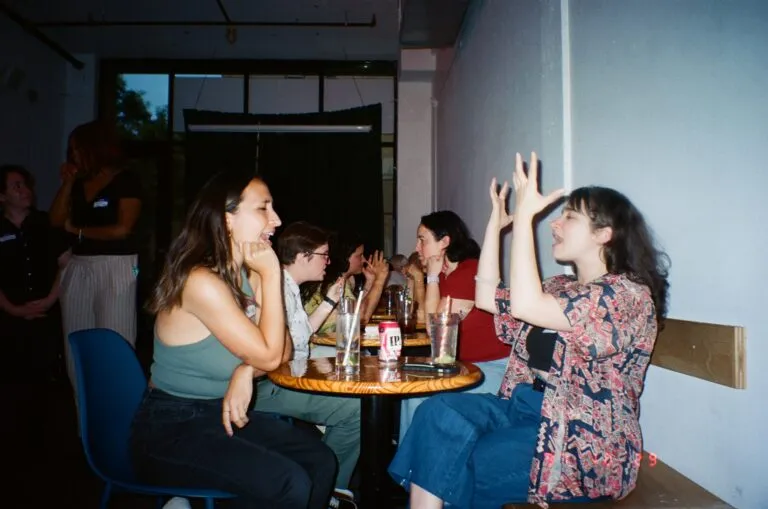 Several groups of young adults sit in a bar having animated conversations.