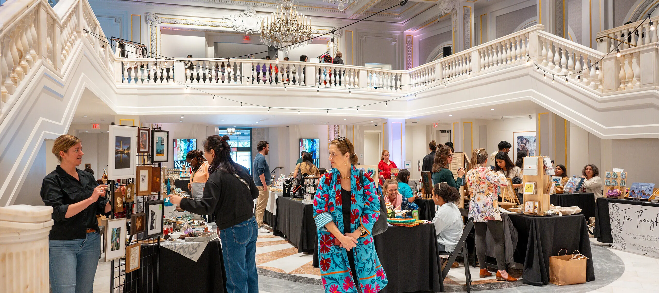 Various people walk around tables showcasing products of different local vendors.